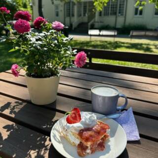 Kuvassa on kakkupala, kahvi ja kukka.